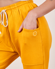 Cropped Rolled Cuff Sweatpants in Mustard Yellow front pocket close up. Alex has her hand in the pocket.