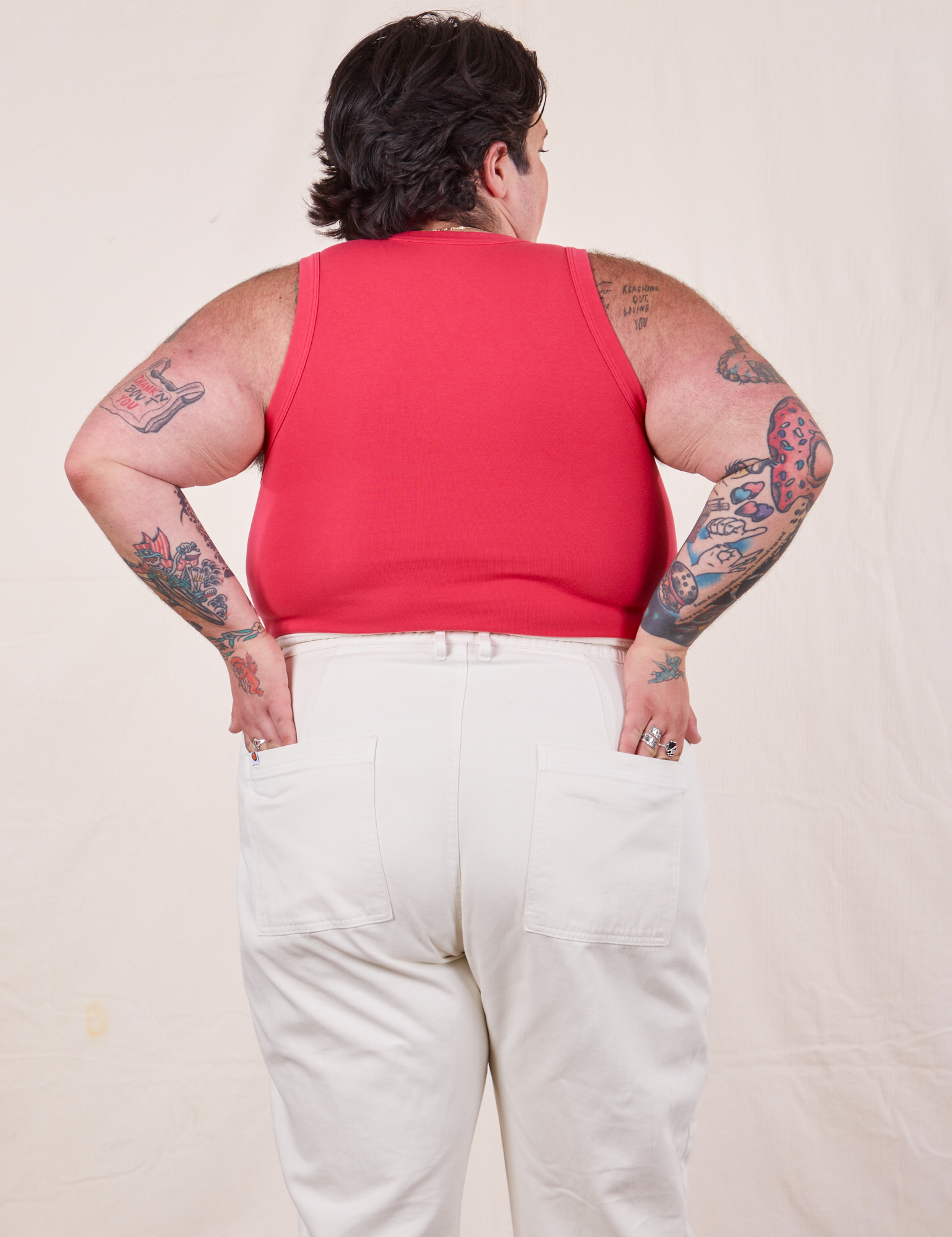 Back view of Tank Top in Hot Pink and vintage off-white Western Pants. Sam has their hands in both back pockets.