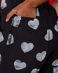 Close up of Kandia's hand in the back pocket of Paintstamped Heart Work Pants in Black