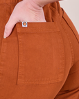 Close up of Alex's hand in the back pocket of Western Pants in Burnt Terracotta