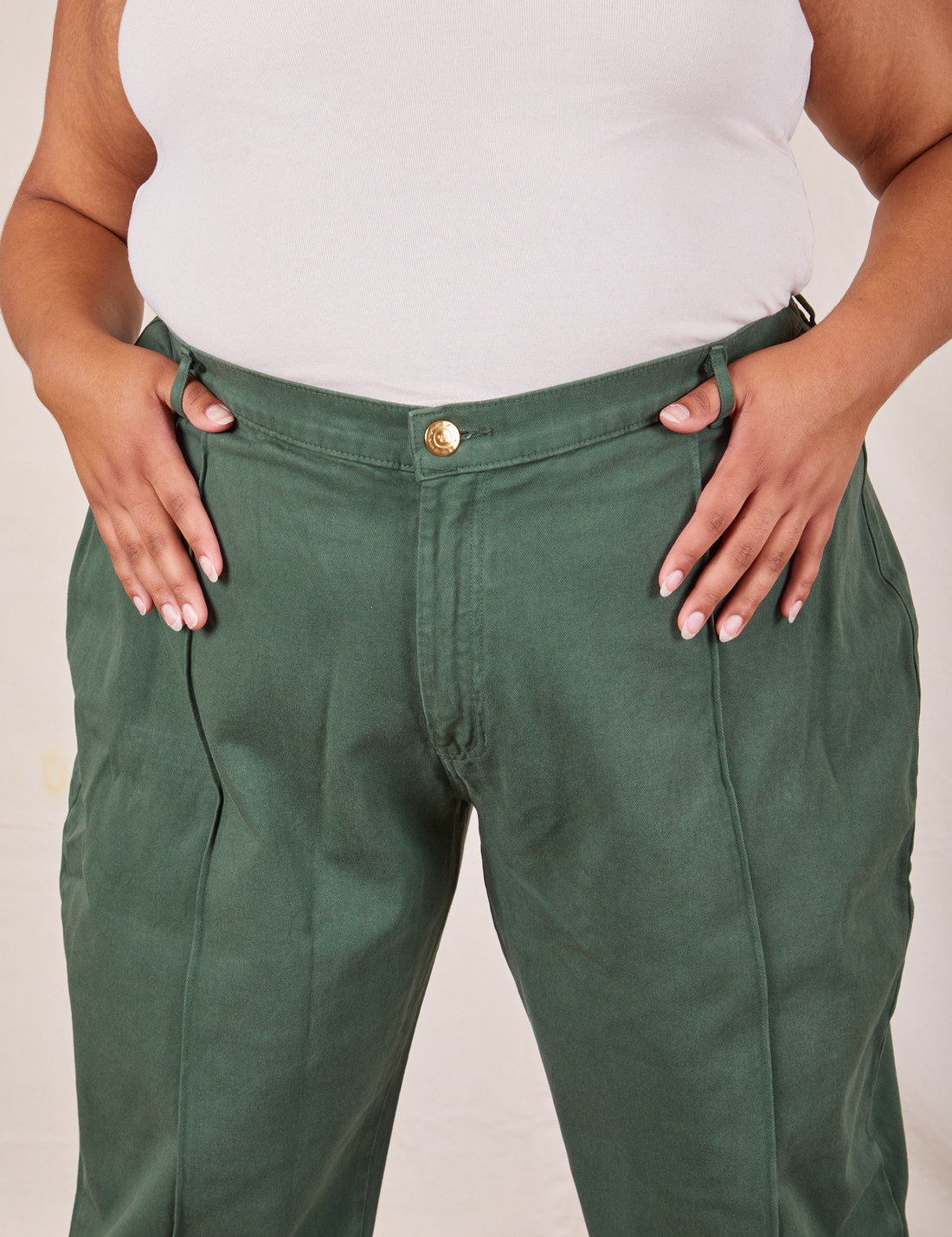 Front close up of Western Pants in Dark Green Emerald. Alicia has both her thumbs through the belt loop.