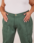 Front close up of Western Pants in Dark Green Emerald. Alicia has both her thumbs through the belt loop.