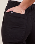 Back pocket close up of Work Pants in Basic Black. Soraya has her hand in the pocket