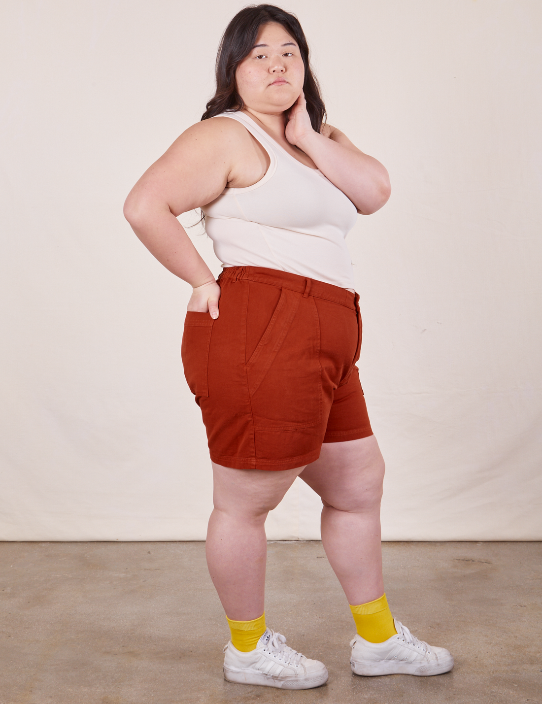 Side view of Classic Work Shorts in Paprika and vintage off-white Tank Top worn by Ashley