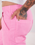 Action Pants in Bubblegum Pink side close up. Jesse has their hand in the back pocket.