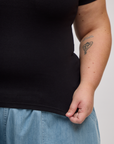 Close up of Juliet holding the bottom hem of Baby Tee in Basic Black