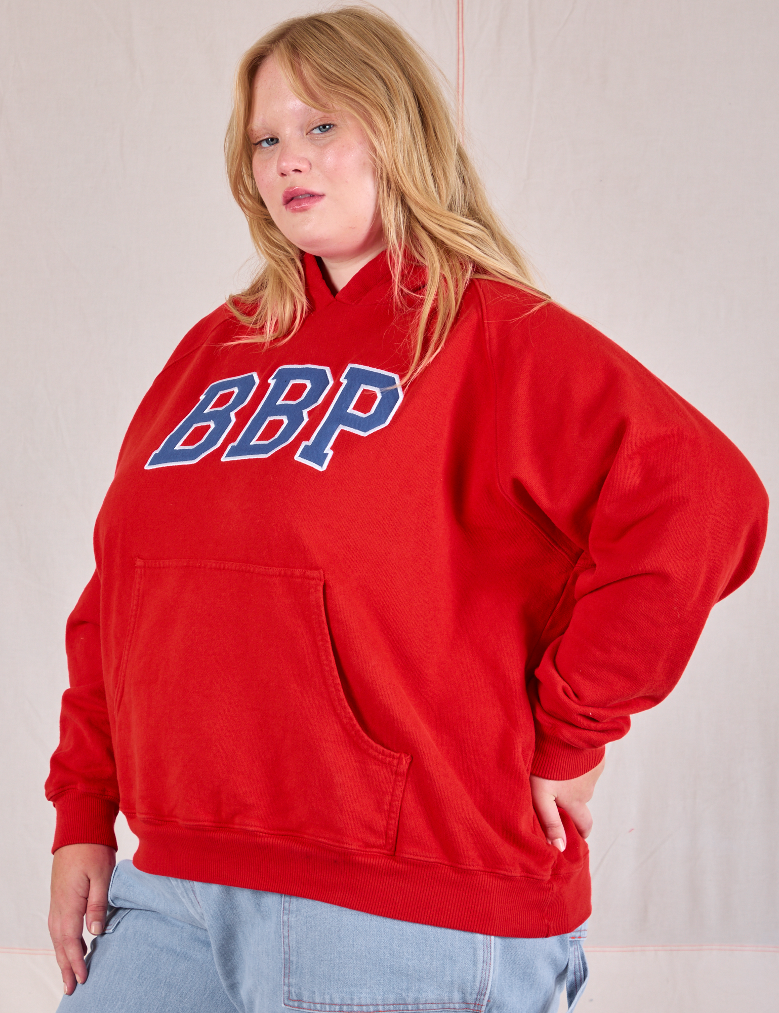 Angled front view of Collegiate Hoodie in Mustang Red on Juliet