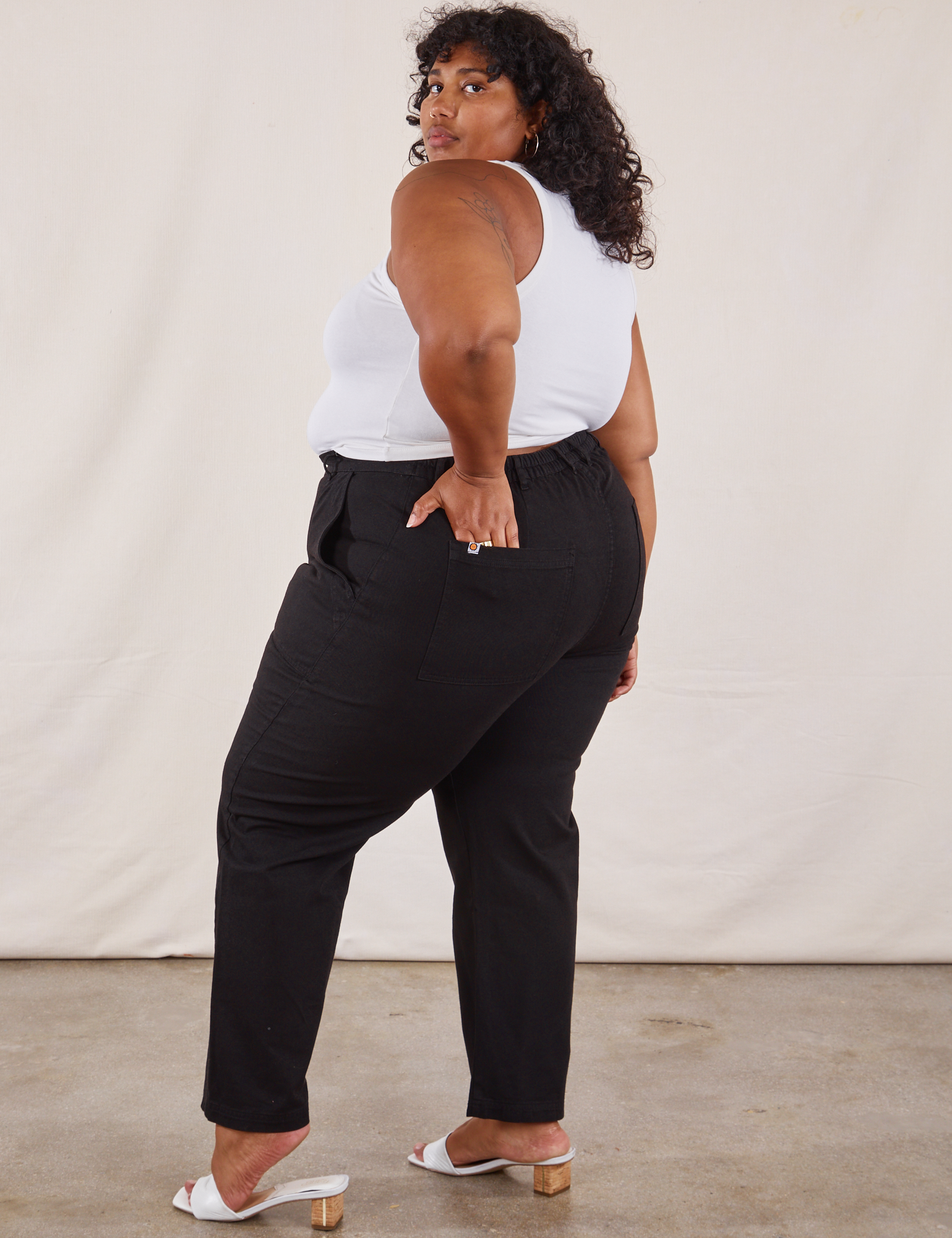 Angled back view of Work Pants in Black and Tank Top in vintage tee off-white on Morgan