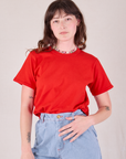 Alex is wearing Burly Tee in Mustang Red tucked into light wash Wide Leg Trousers