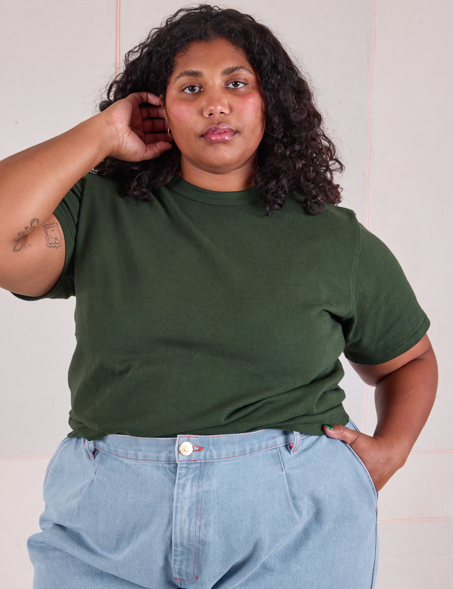 Morgan is wearing Burly Tee in Swamp Green tucked into light wash Denim Wide Leg Trousers