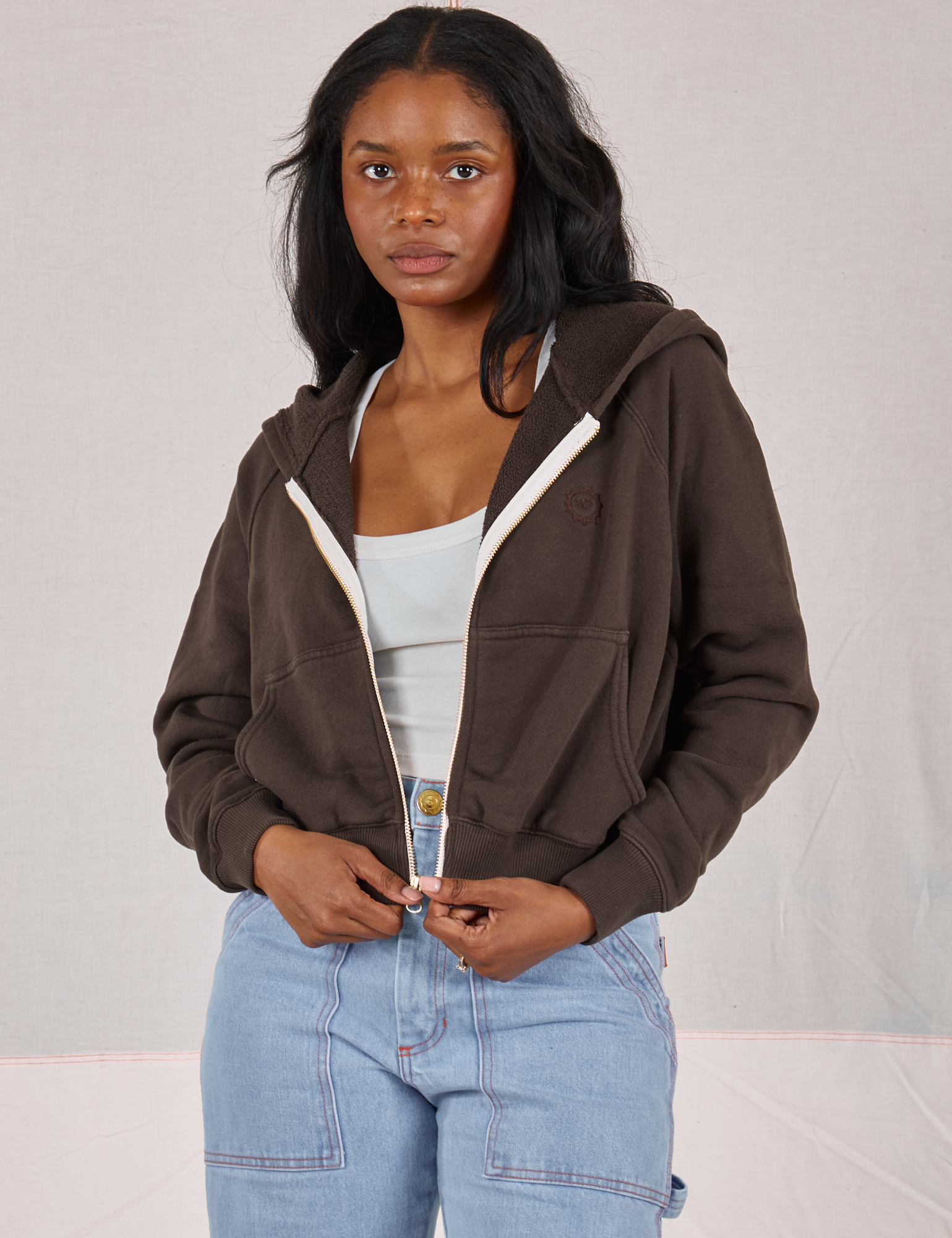 Kandia is 5&#39;3&quot; and wearing P Cropped Zip Hoodie in Espresso Brown paired with a vintage off-white Cropped Tank and light wash Carpenter Jeans