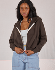 Kandia is 5'3" and wearing P Cropped Zip Hoodie in Espresso Brown paired with a vintage off-white Cropped Tank and light wash Carpenter Jeans