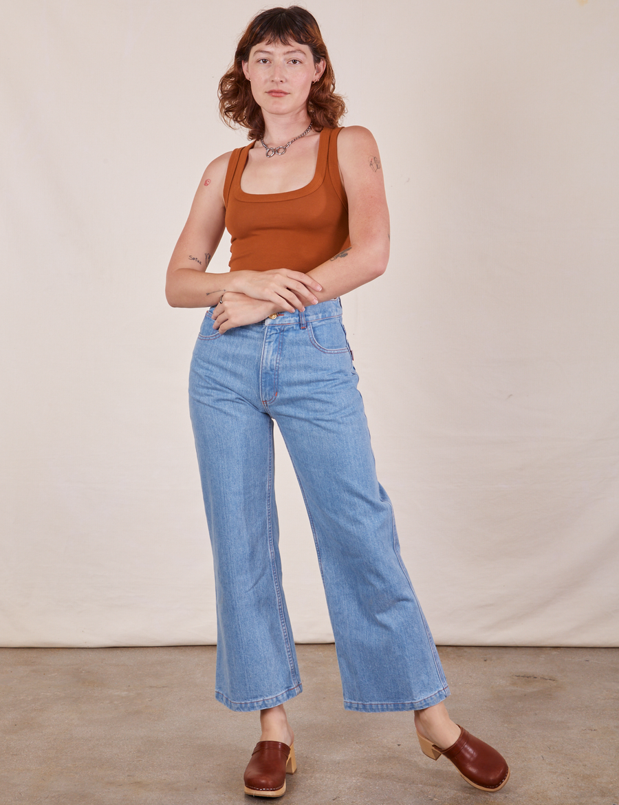 Alex is 5'8" and wearing P Cropped Tank Top in Burnt Terracotta paired with light wash Sailor Jeans