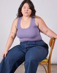 Ashley is sitting in a chair and wearing Cropped Tank Top in Faded Grape paired with dark wash Indigo Wide Leg Trousers