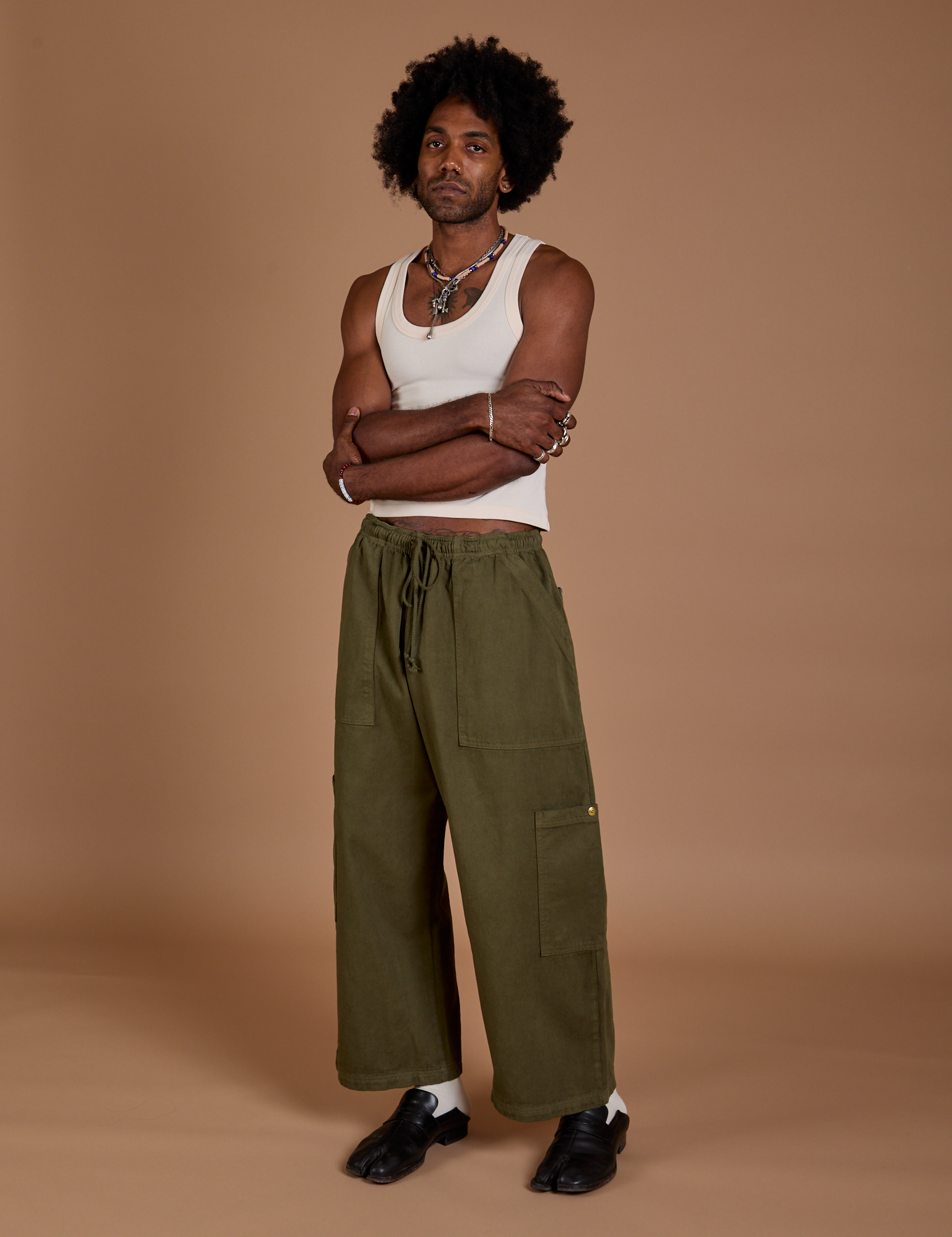 Angled front view of Drop Pocket Cargo Pants in Surplus Green and Tank Top in Vintage Tee White on Jerrod