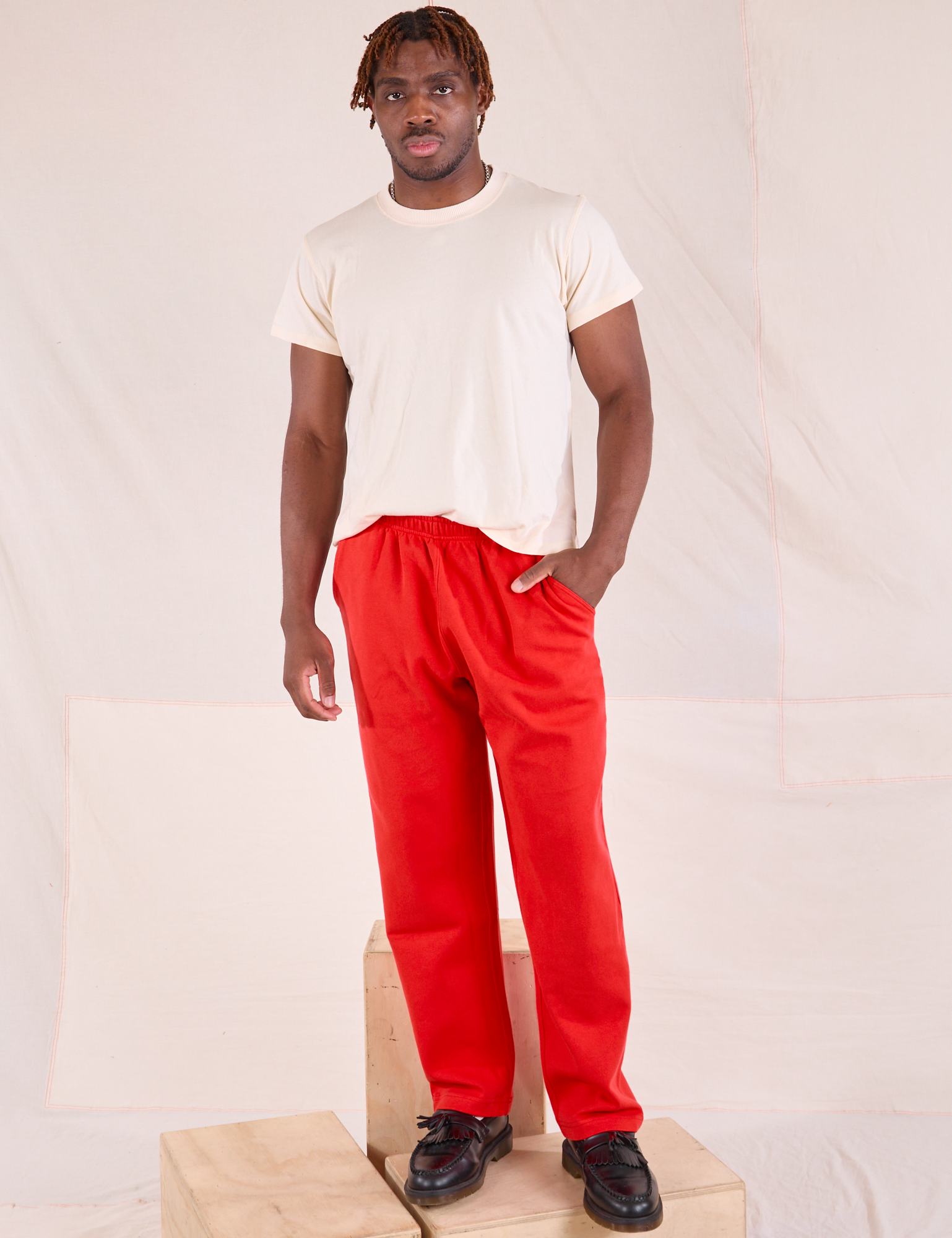 Issac is wearing Easy Pants in Mustang Red and Organic Vintage Tee in Vintage Tee Off-White