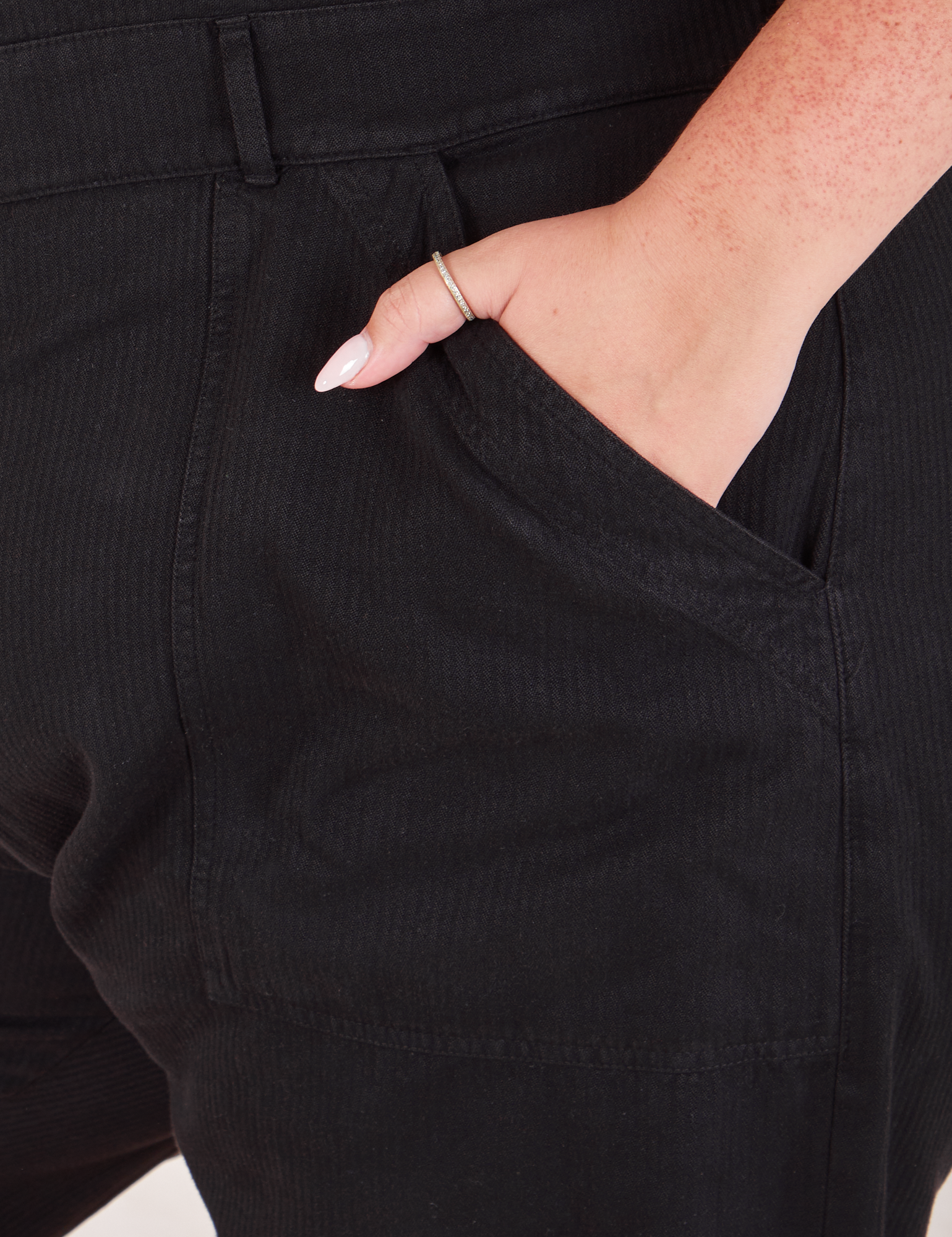 Heritage Short Sleeve Jumpsuit in Basic Black front pocket close up with Katie&#39;s hand in it.