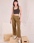 Alex is wearing Mid-Rise Pleated Trousers in Desert Brown and espresso brown Cropped Tank