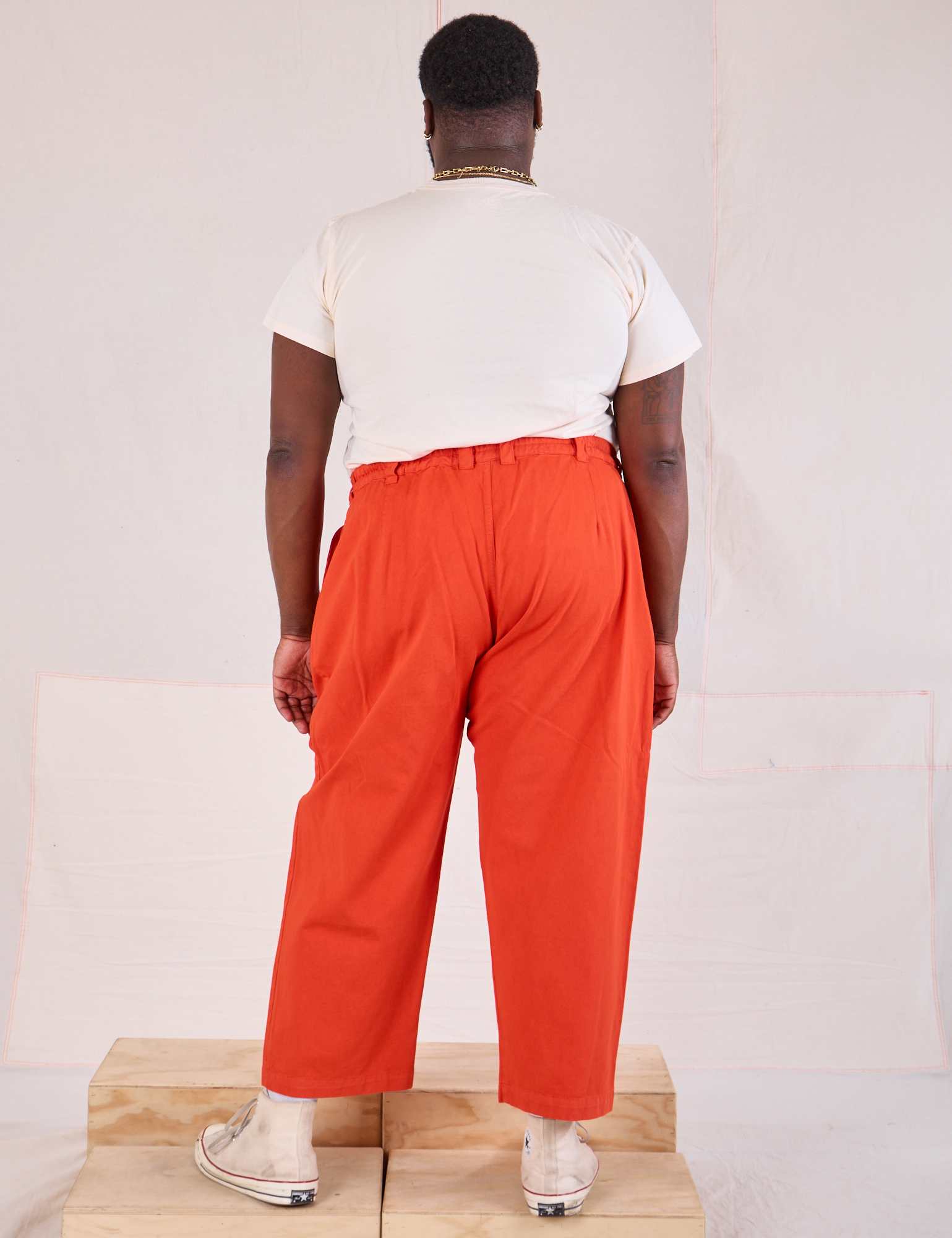 Back view of Mid-Rise Pleated Trousers in Chili Red and Organic Vintage Tee in vintage tee off-white on Elijah