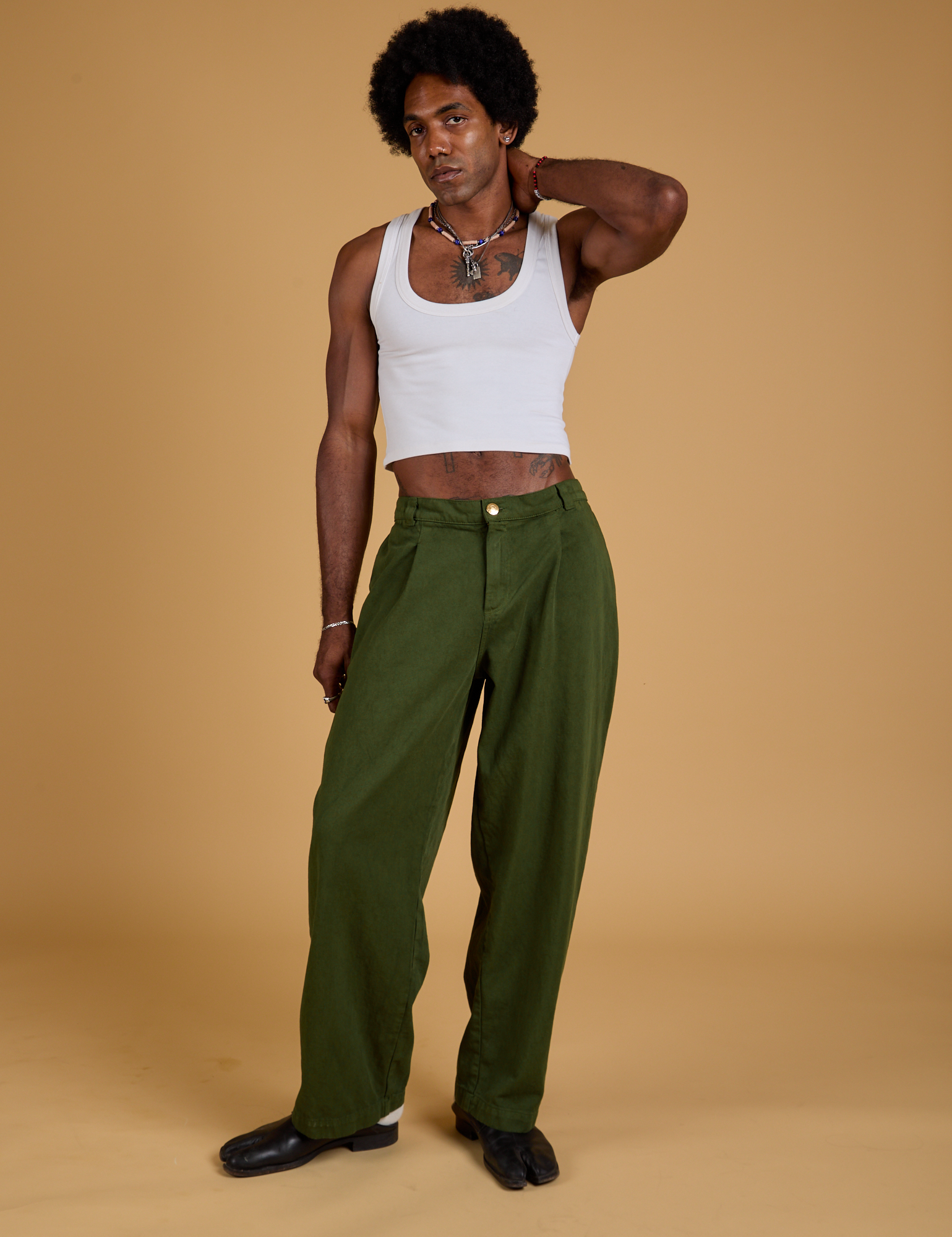 Jerrod is wearing Baggy Mid-Rise Trousers in Evergreen and vintage tee white Cropped Tank