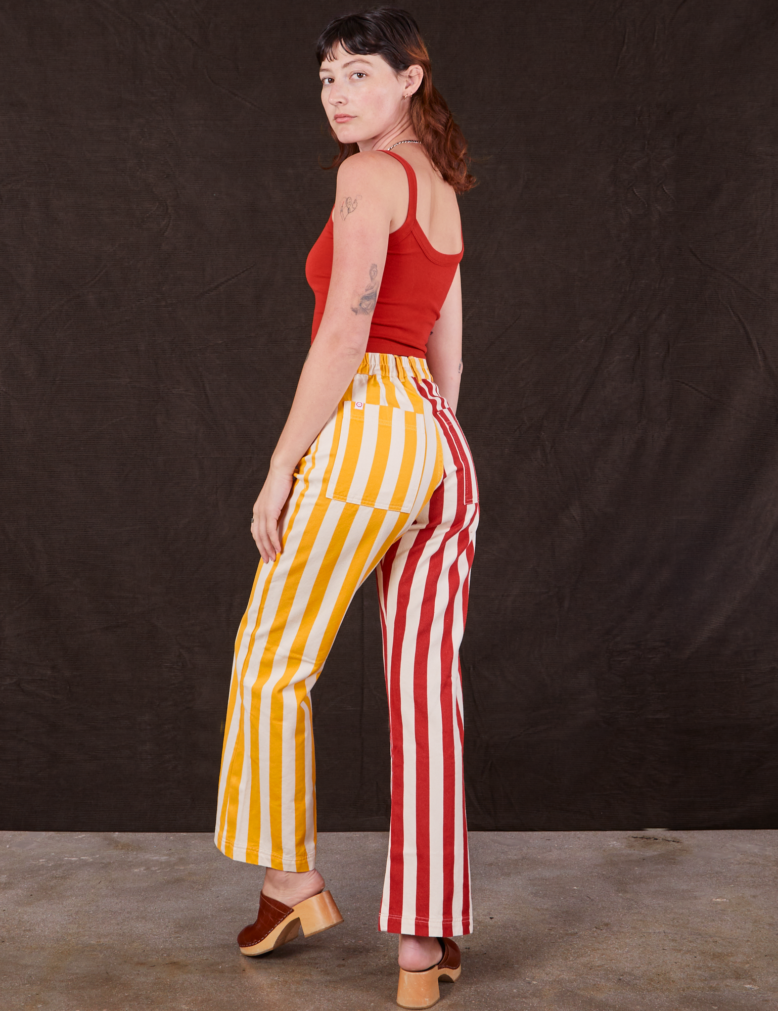 Angled back view of Western Pants in Ketchup/Mustard Stripes and mustang red Cami on Alex