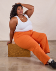 Work Pants in Construction Orange and Cropped Tank worn by Morgan sitting on a wooden box.