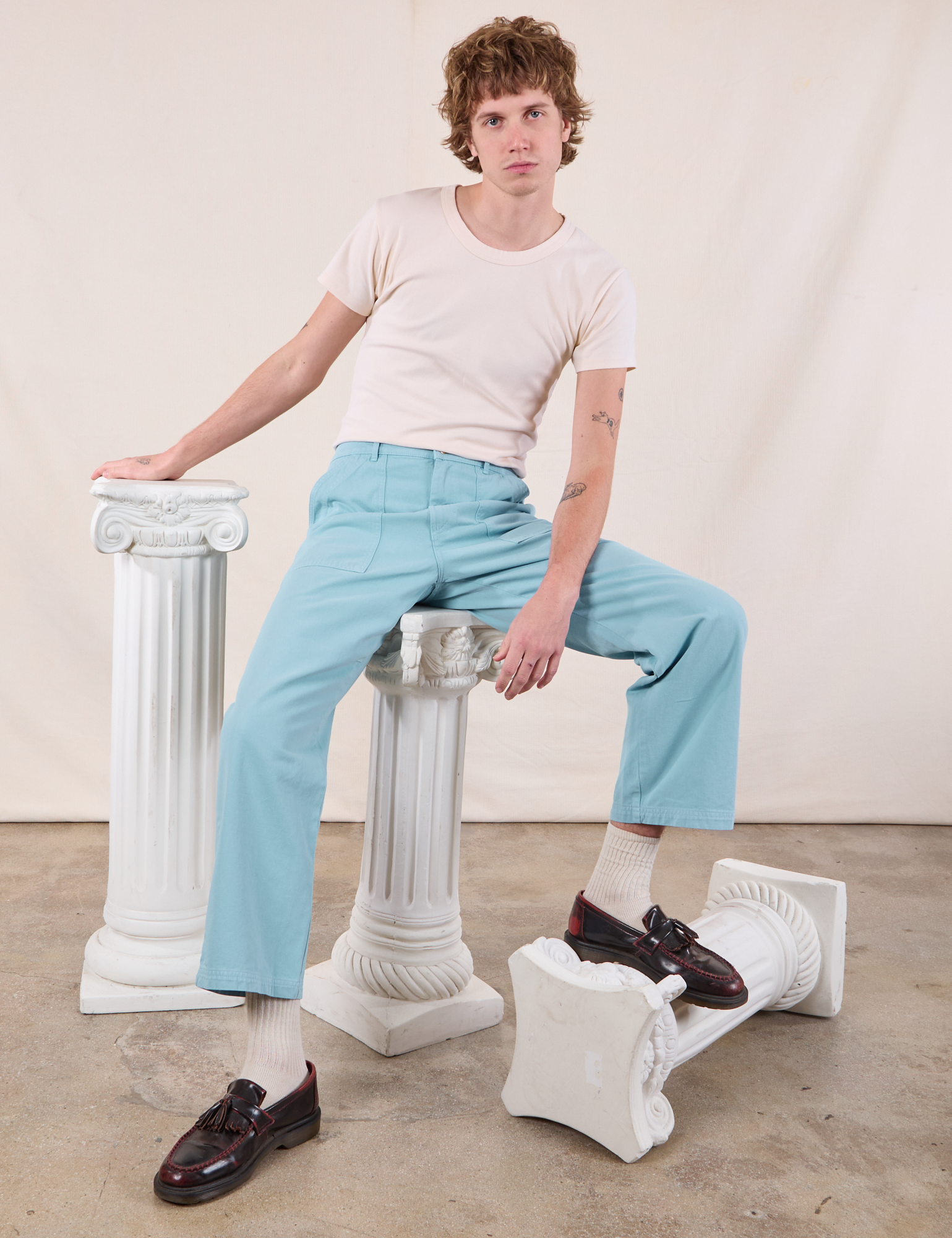 Work Pants in Baby Blue on Quinn sitting on a column