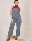 Tiara is 5'4" and wearing XS Railroad Stripe Denim Original Overalls paired with paprika Sleeveless Turtleneck