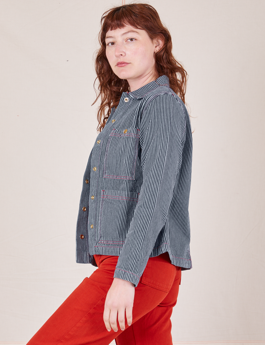 Side view of Railroad Stripe Denim Work Jacket paired with paprika Western Pants worn by Alex