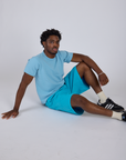 Isaac is wearing Longline Work Shorts in Hawaiian Blue and baby blue Organic Vintage Tee