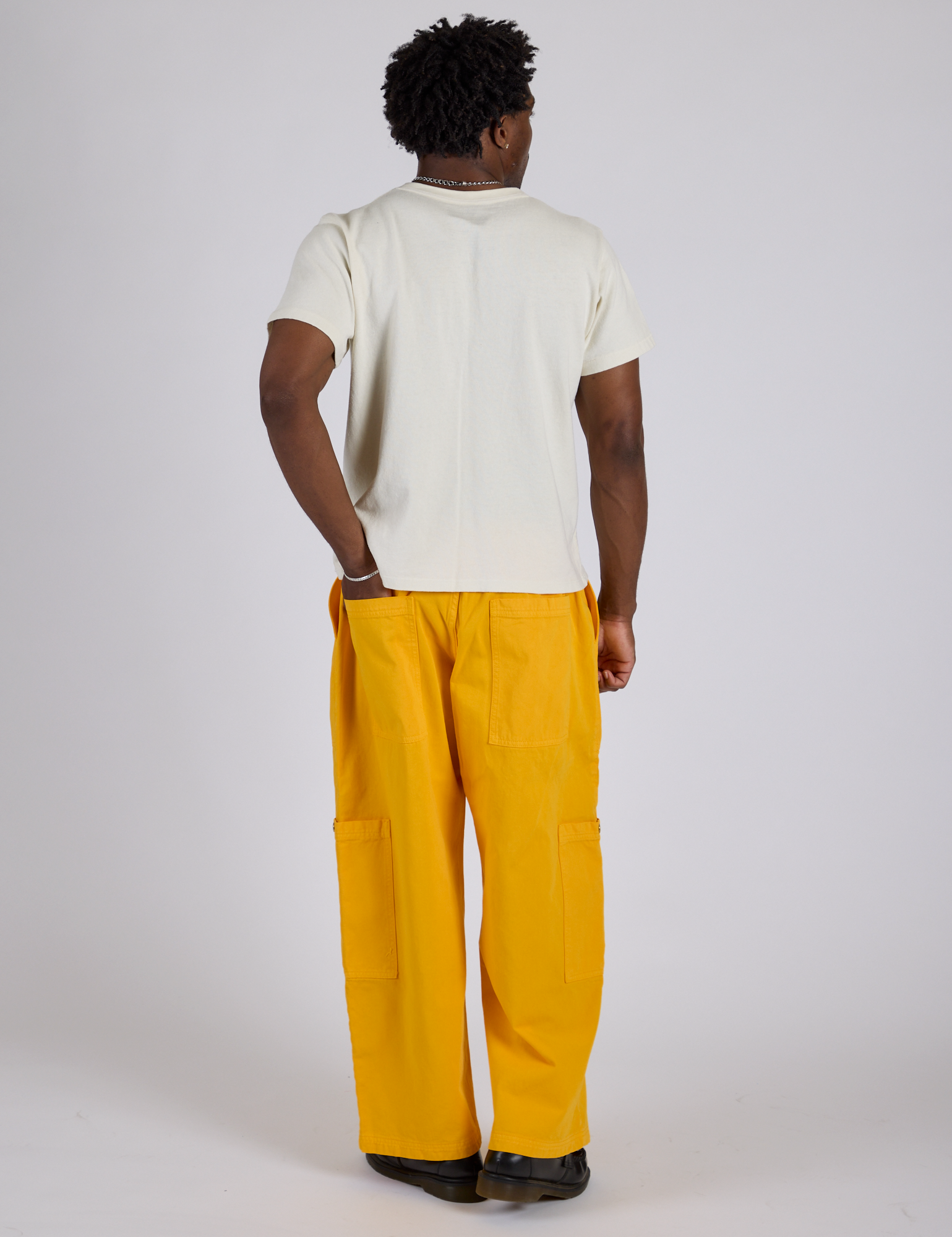 Back view of Drop Pocket Cargo Pants in Sunshine Yellow and Organic Vintage Tee in Vintage Tee White on Isaac