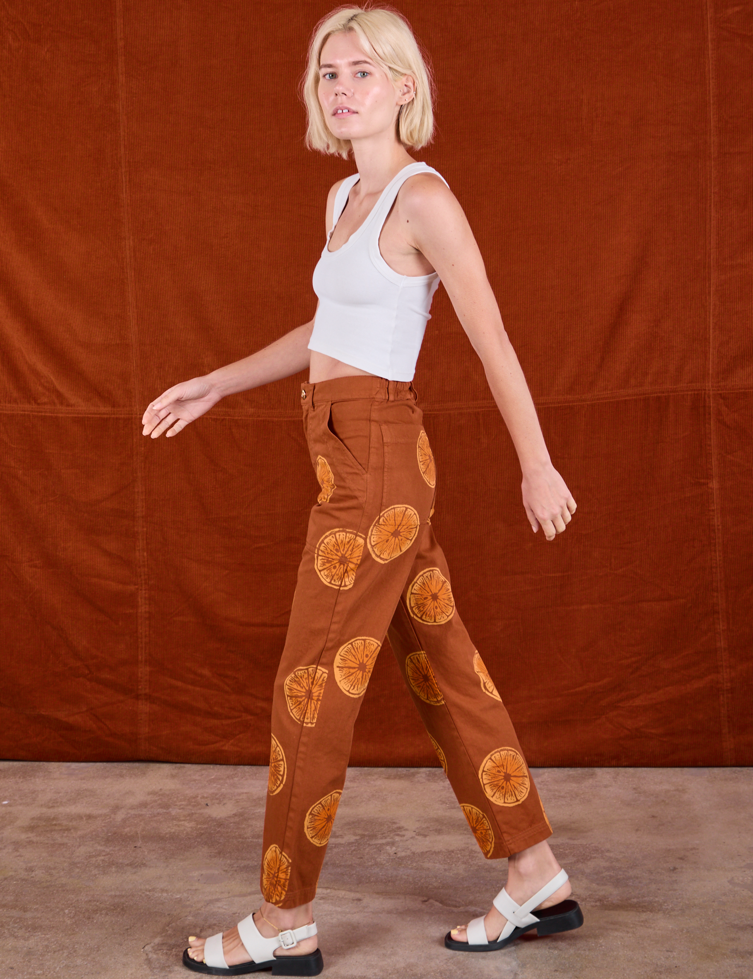 Side view of Paintstamped Work Pants in Orange and Cropped Tank in Vintage Tee Off-White on Madeline