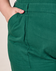 Front pocket close up of Short Sleeve Jumpsuit in Hunter Green. Marielena has her hand in the pocket.