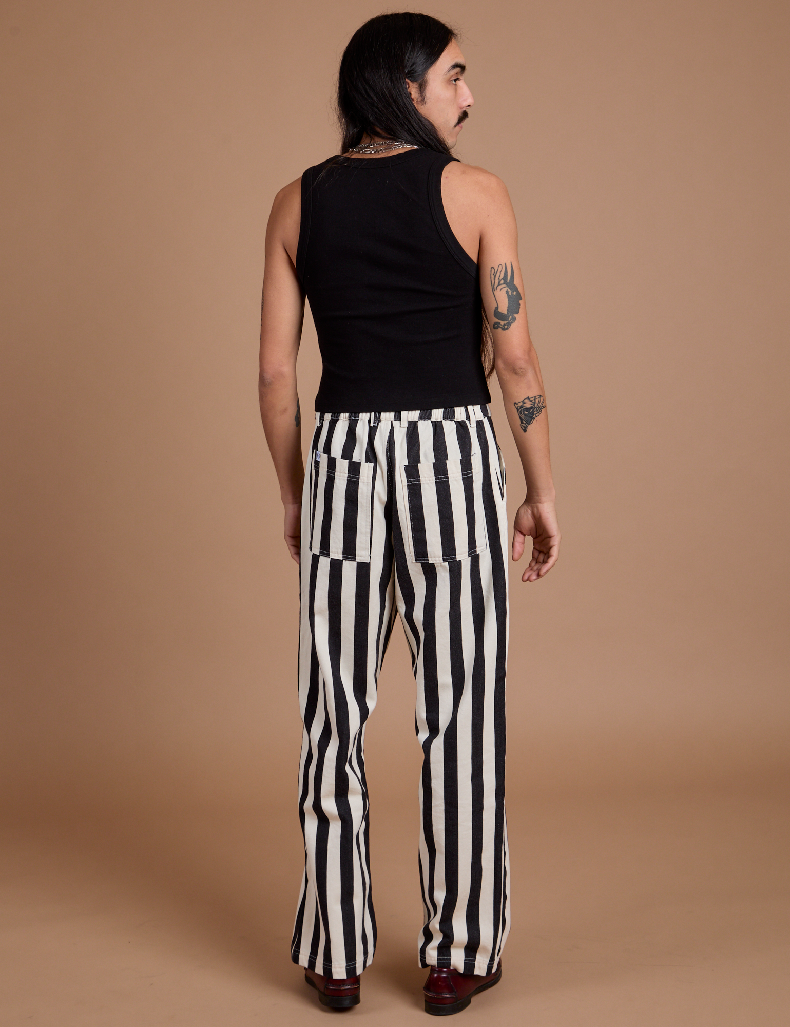 Back view of Black Stripe Work Pants in White and black Cropped Tank on Anthony