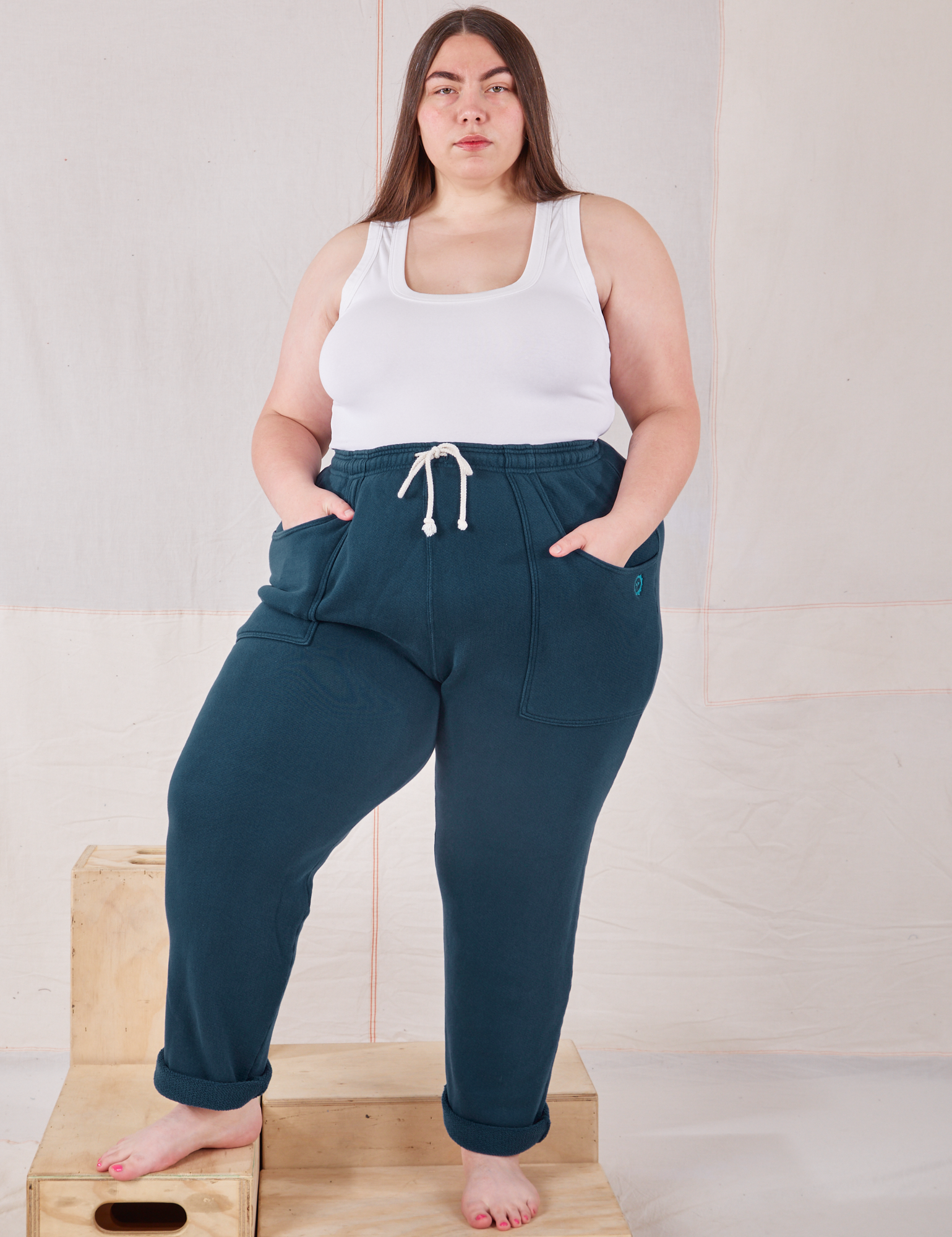 Marielena is 5&#39;8&quot; and wearing 1XL Rolled Cuff Sweat Pants in Lagoon paired with Cropped Tank in vintage tee off-white