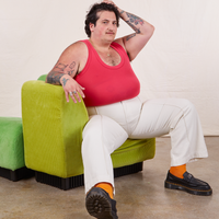 Sam is sitting in a green upholstered chair wearing Tank Top in Hot Pink and vintage off-white Western Pants
