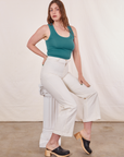 Allison is sitting on a white column wearing Tank Top in Marine Blue paired with vintage off-white Western Pants