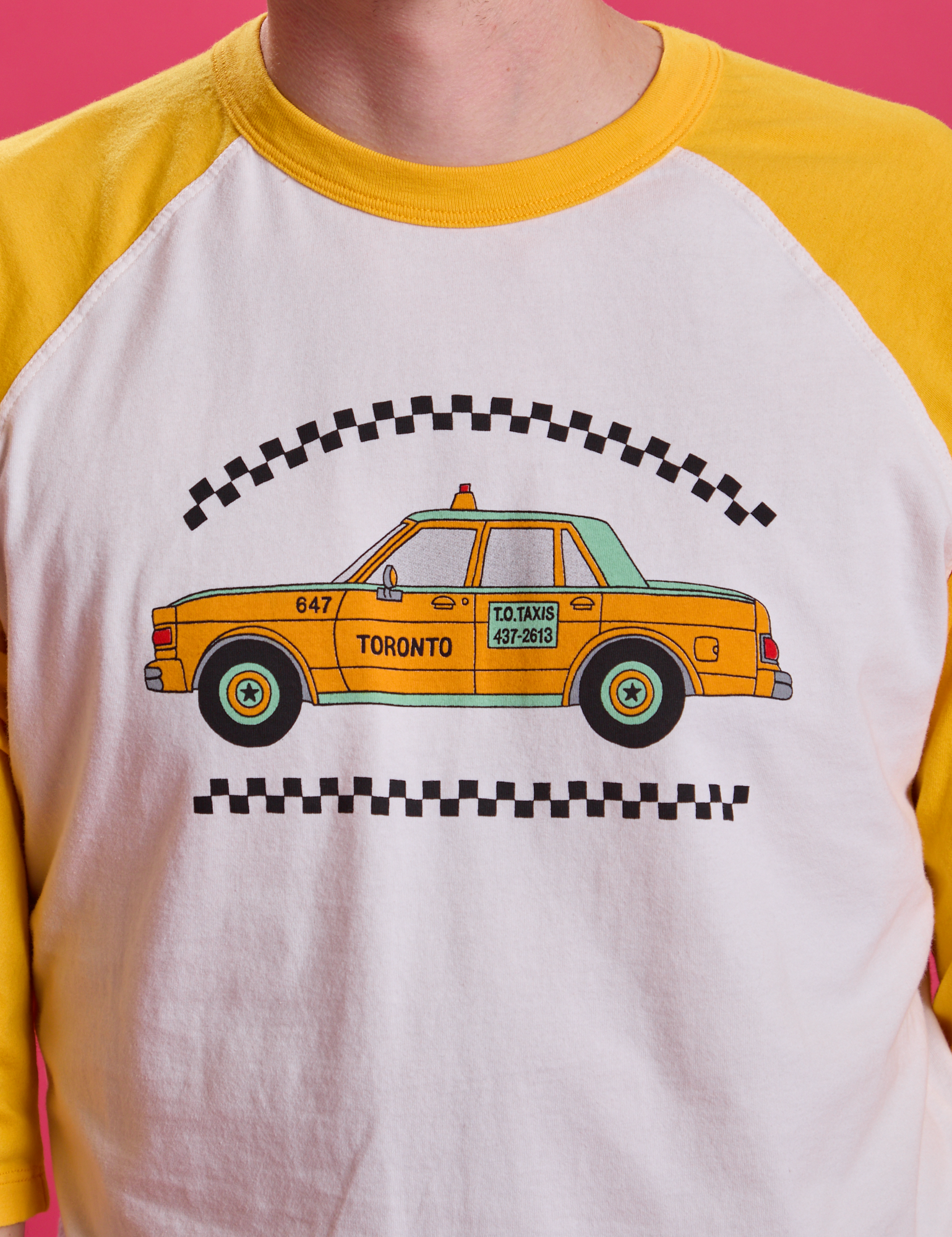 Taxi Raglan Tee in Toronto on Quinn. Yellow taxi graphic on the shirt.