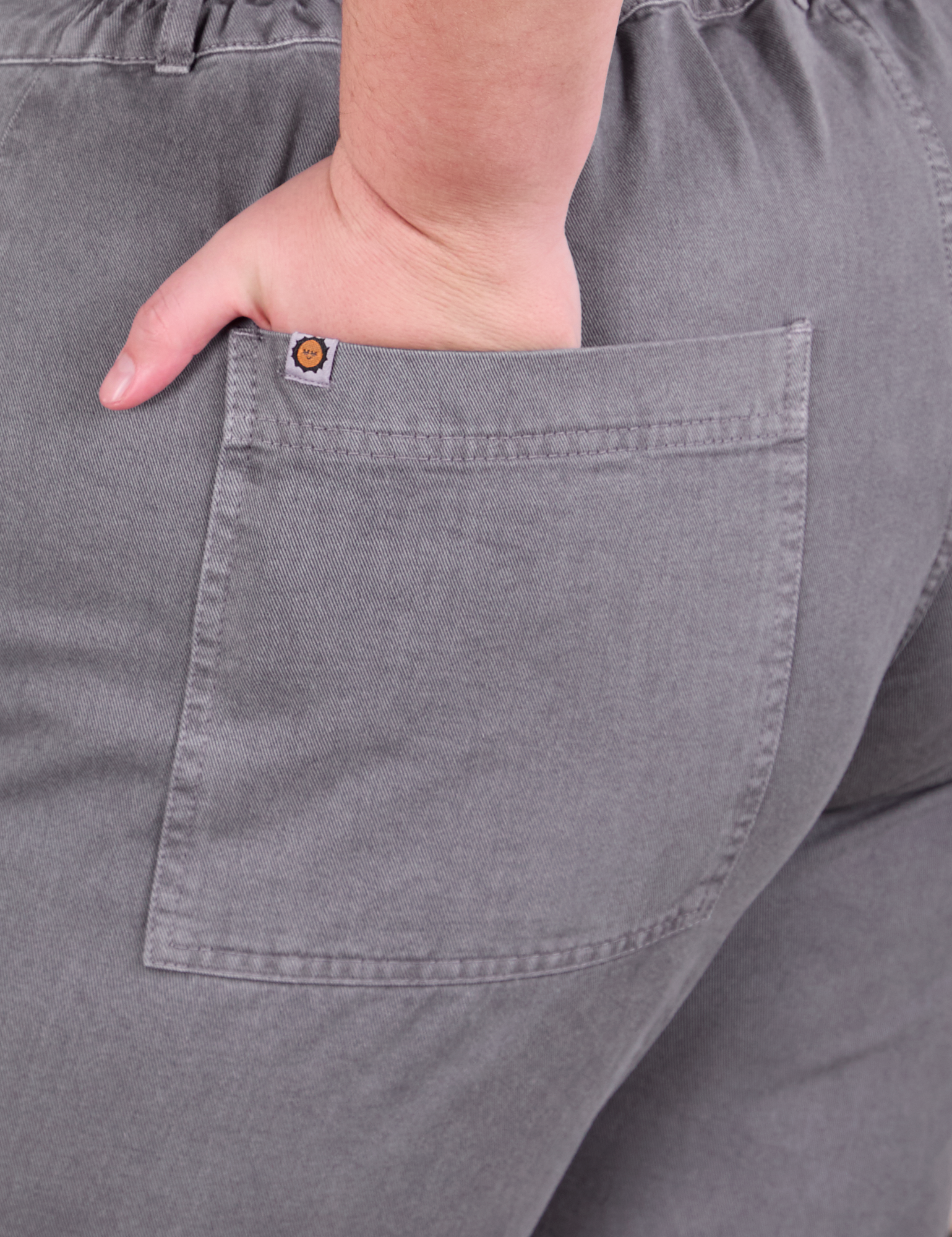 Close up of Marielena&#39;s hand in the back pocket of Short Sleeve Jumpsuit in Washed Grey