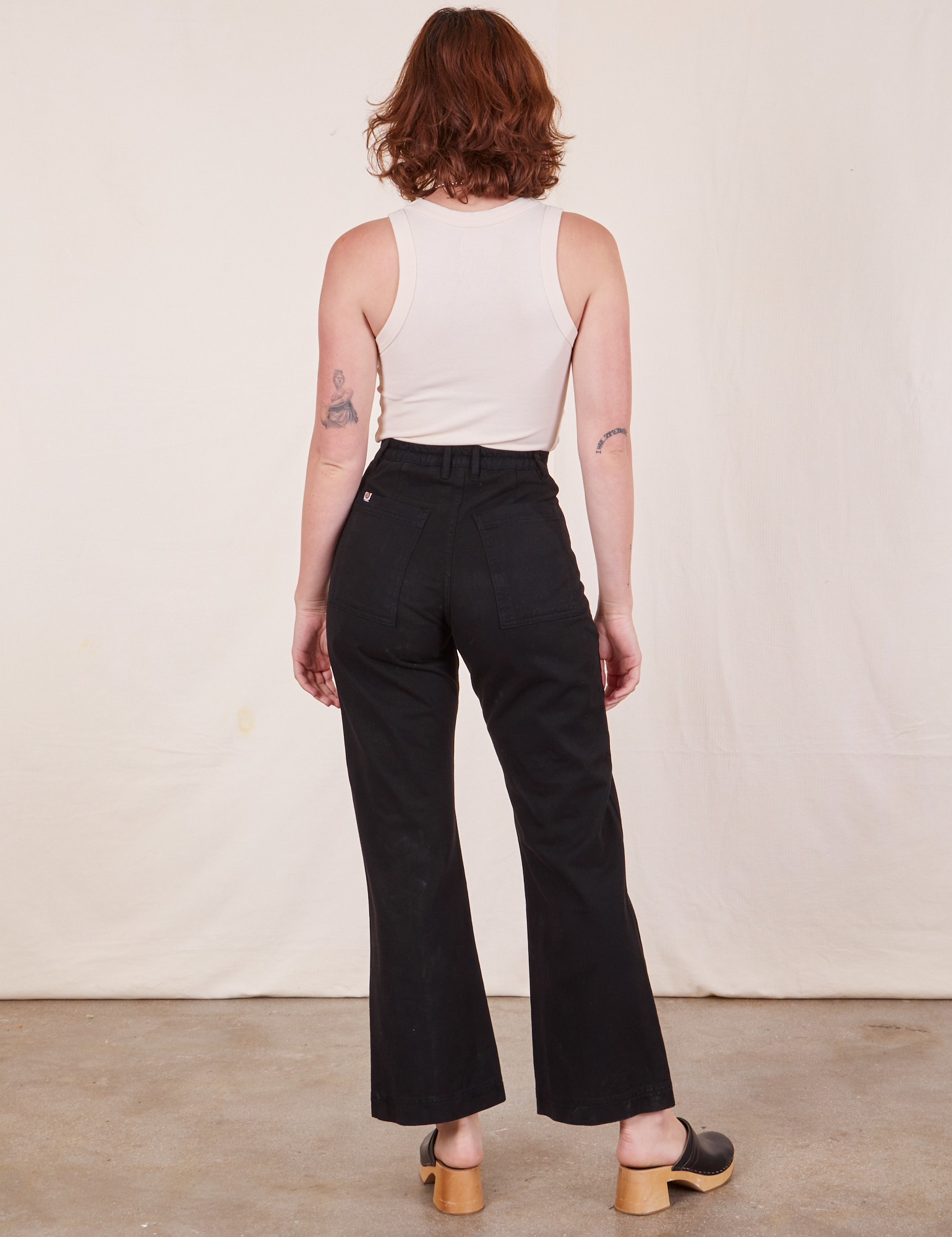 Back view of Western Pants in Basic Black and vintage off-white Tank Top worn by Alex