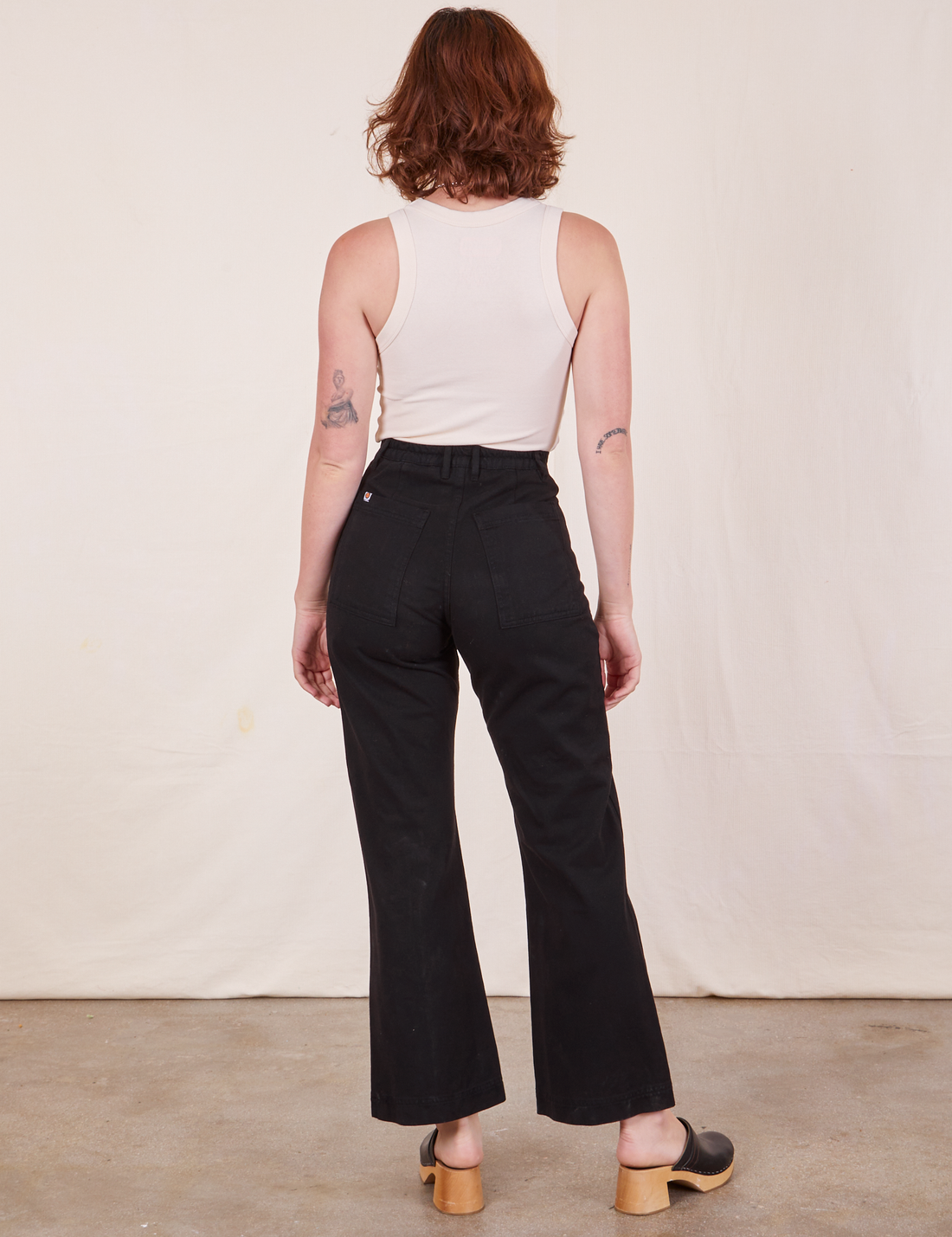 Back view of Western Pants in Basic Black and vintage off-white Tank Top worn by Alex