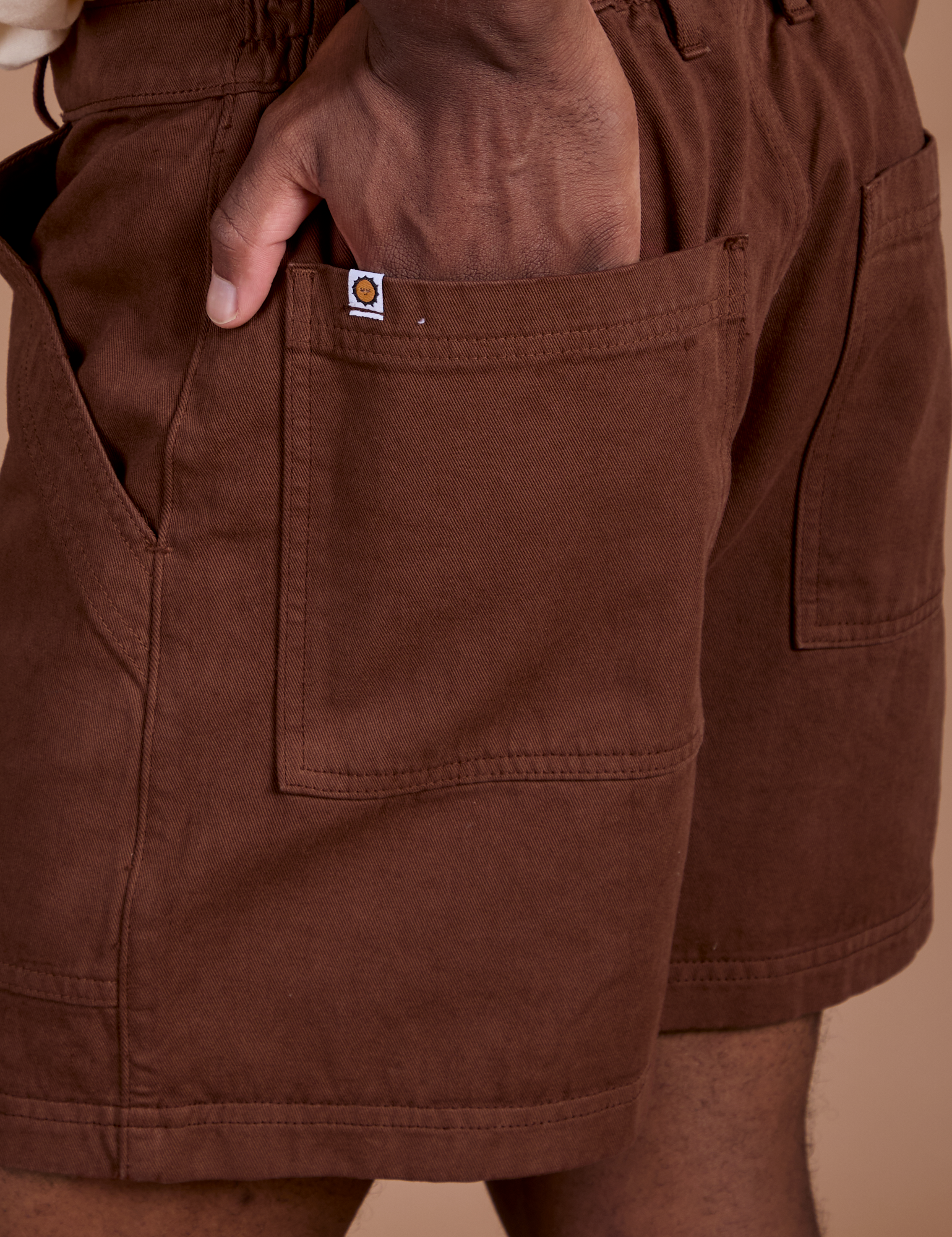 Close up of Isaac's hand in the back pocket of Classic Work Shorts in Fudgesicle Brown