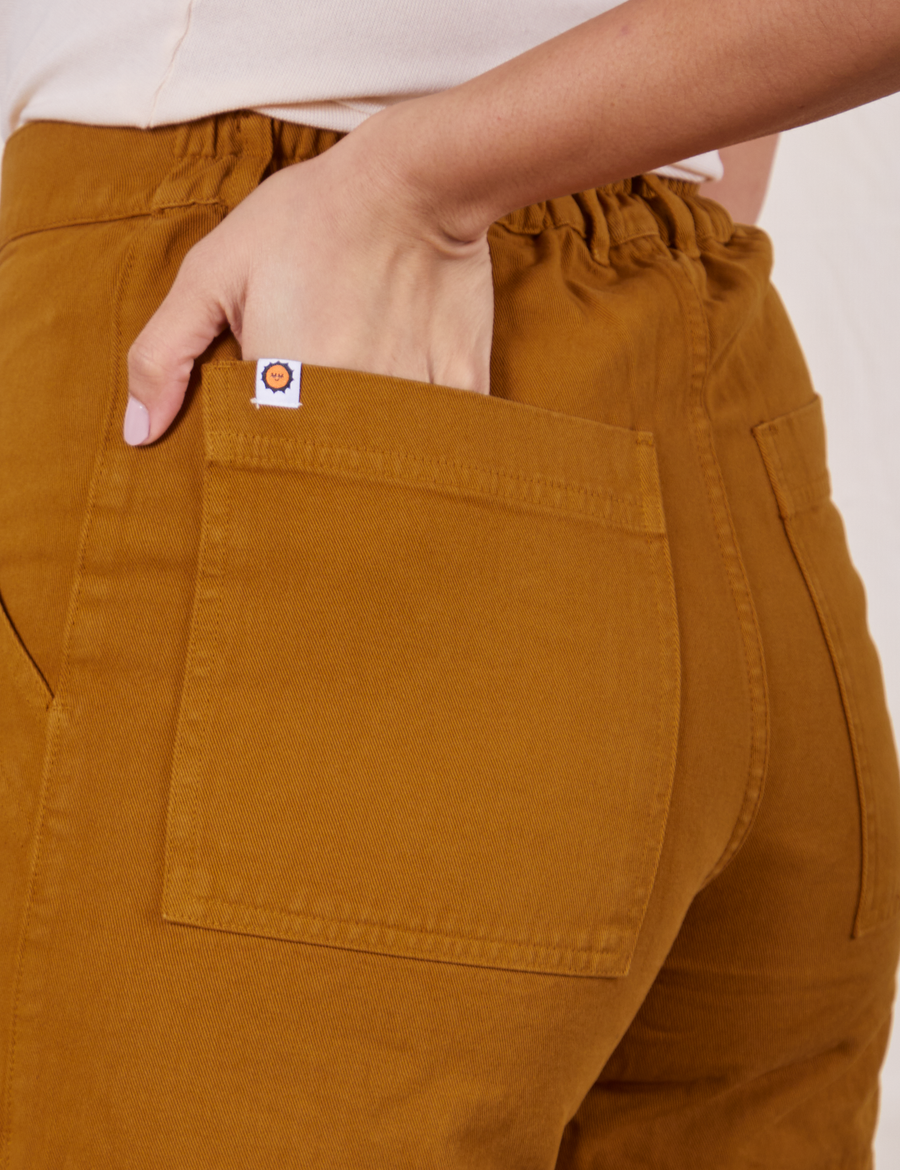 Classic Work Shorts in Spicy Mustard back pocket close up. Tiara has her hand in the back pocket.