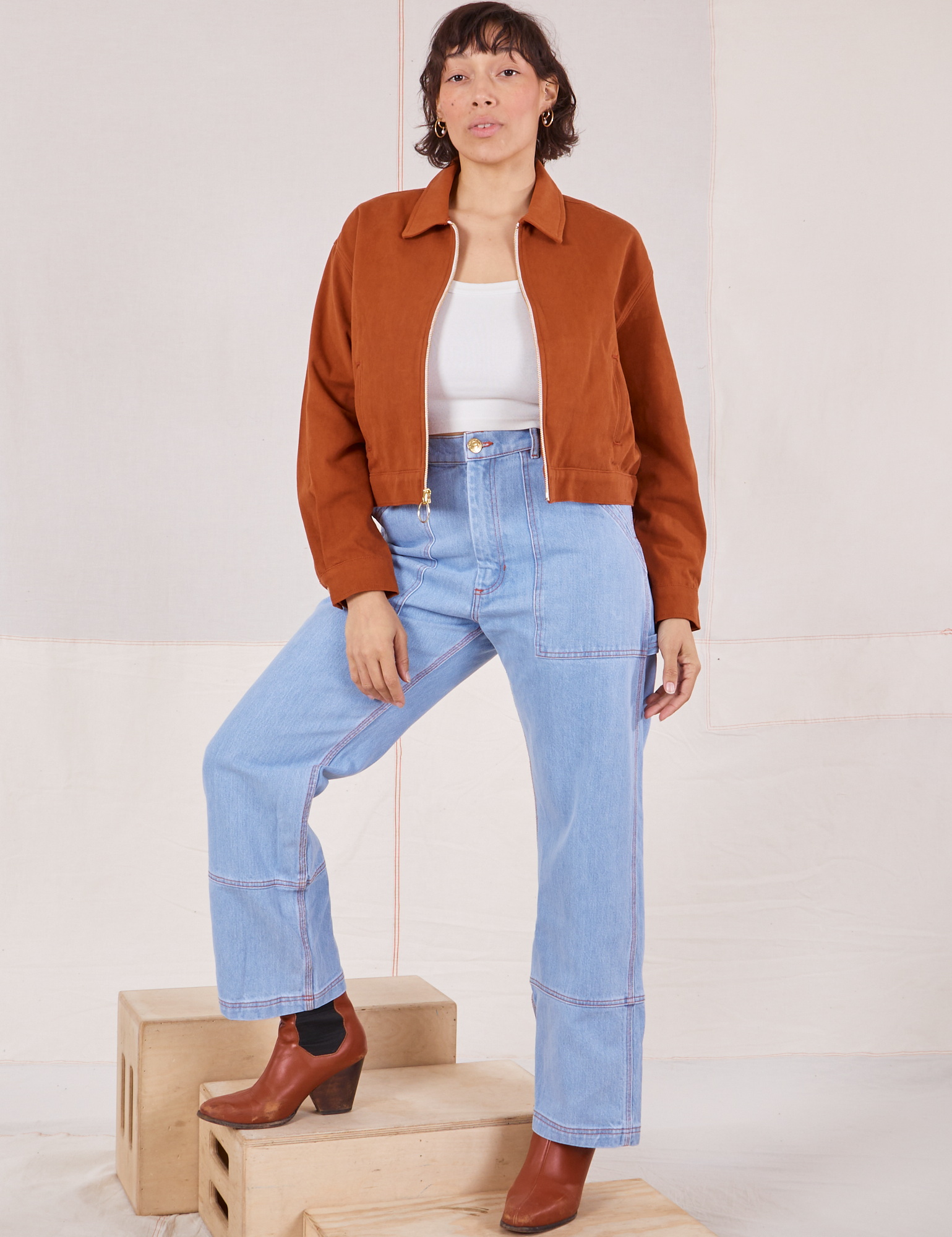 Tiara is wearing Ricky Jacket in Burnt Terracotta with a vintage off-white tee Cami and light wash Carpenter Jeans
