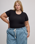 Juliet is wearing Baby Tee in Basic Black tucked into light wash denim drop pocket pants