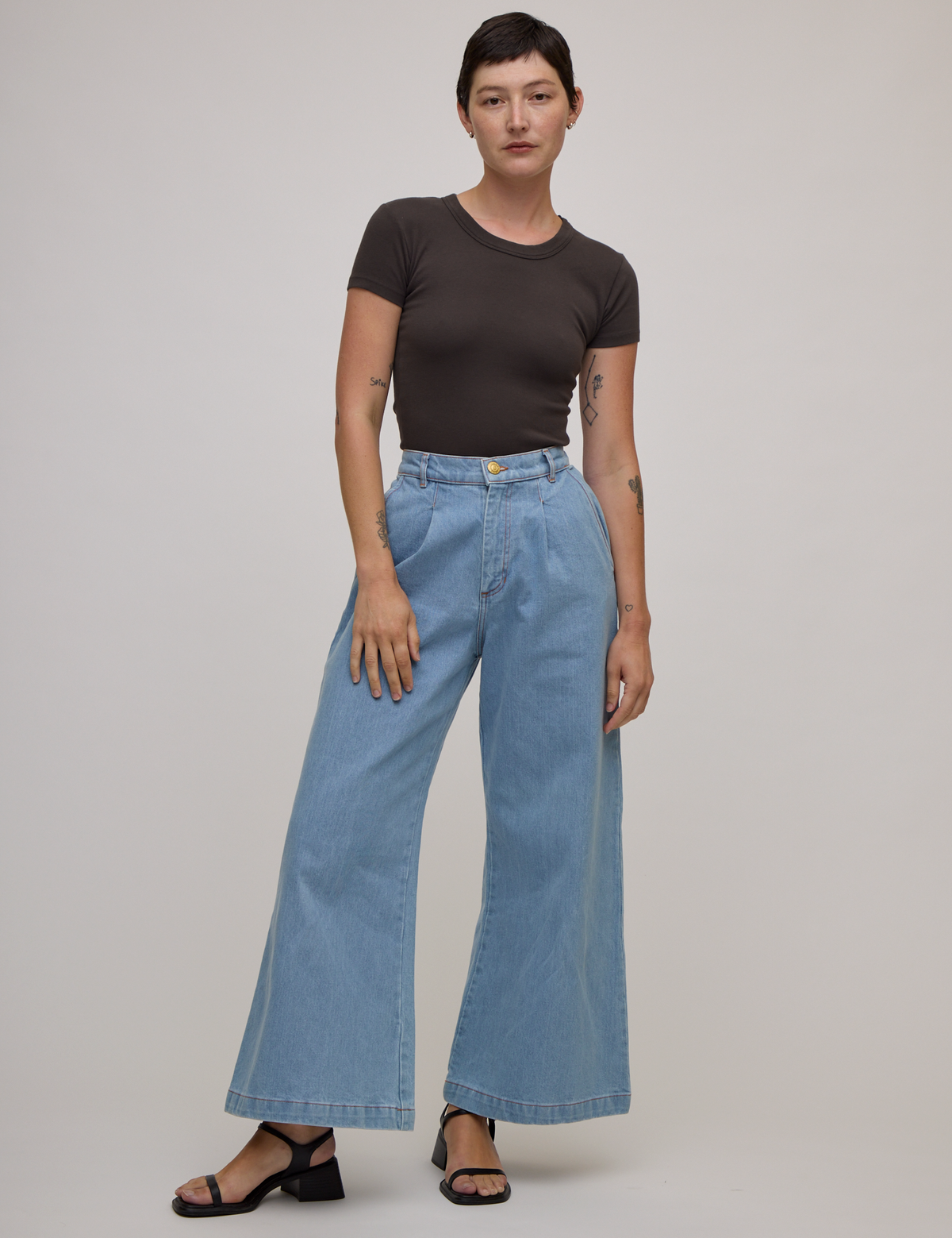 Alex is wearing Baby Tee in Espresso Brown tucked into light wash denim wide leg trousers