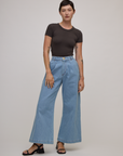 Alex is wearing Baby Tee in Espresso Brown tucked into light wash denim wide leg trousers