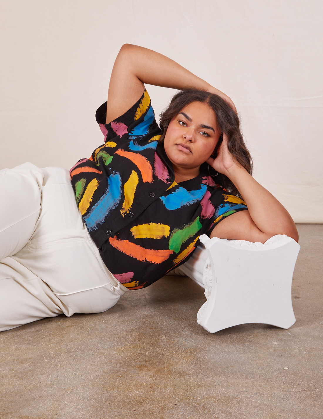 Alicia is laying on her side on the ground wearing Pantry Button Up in Paint Stroke tucked into vintage off-white Western Pants