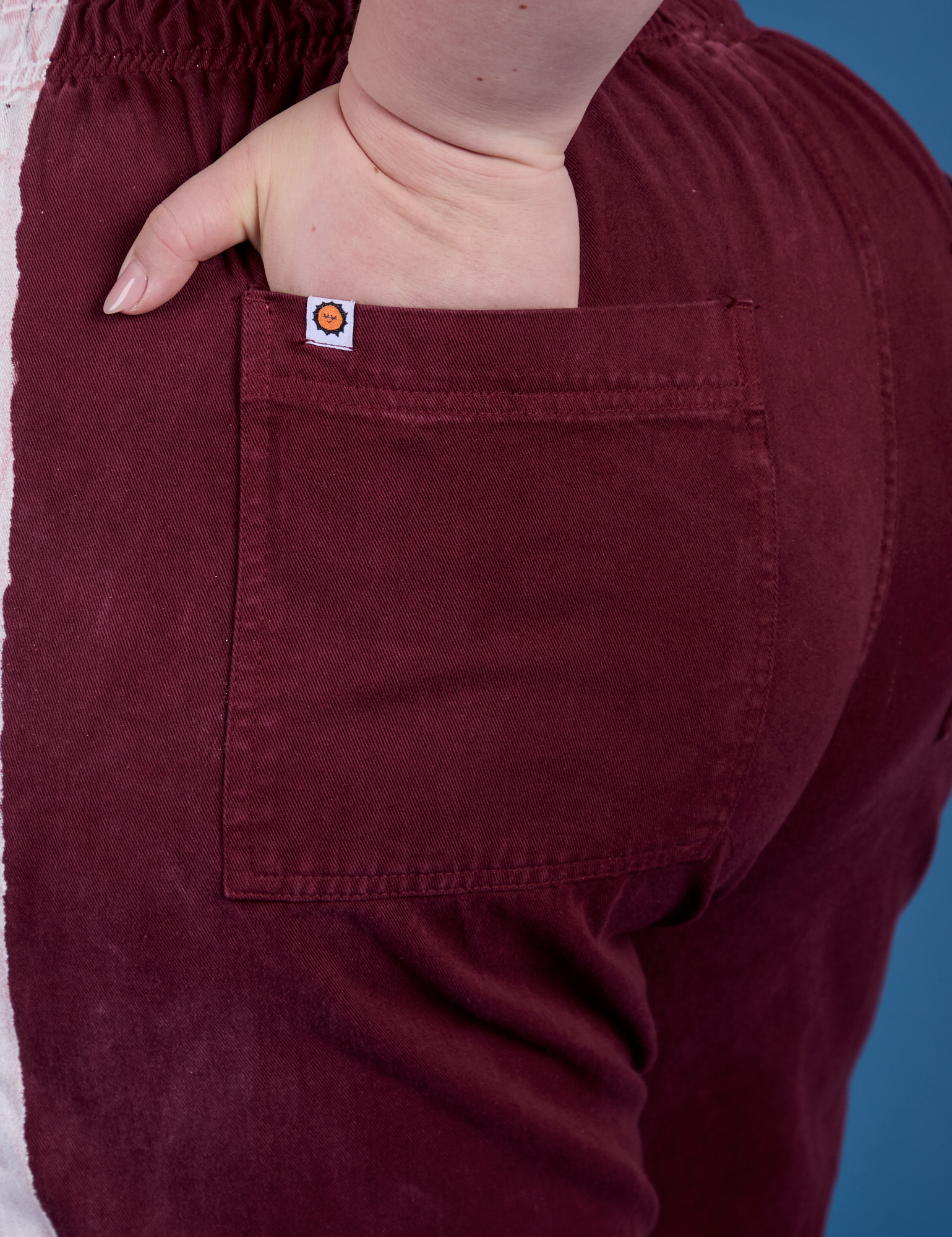 Close up of Ashley's hand in the back pocket of Painted Action Pants in Red Wine
