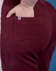 Close up of Ashley's hand in the back pocket of Painted Action Pants in Red Wine